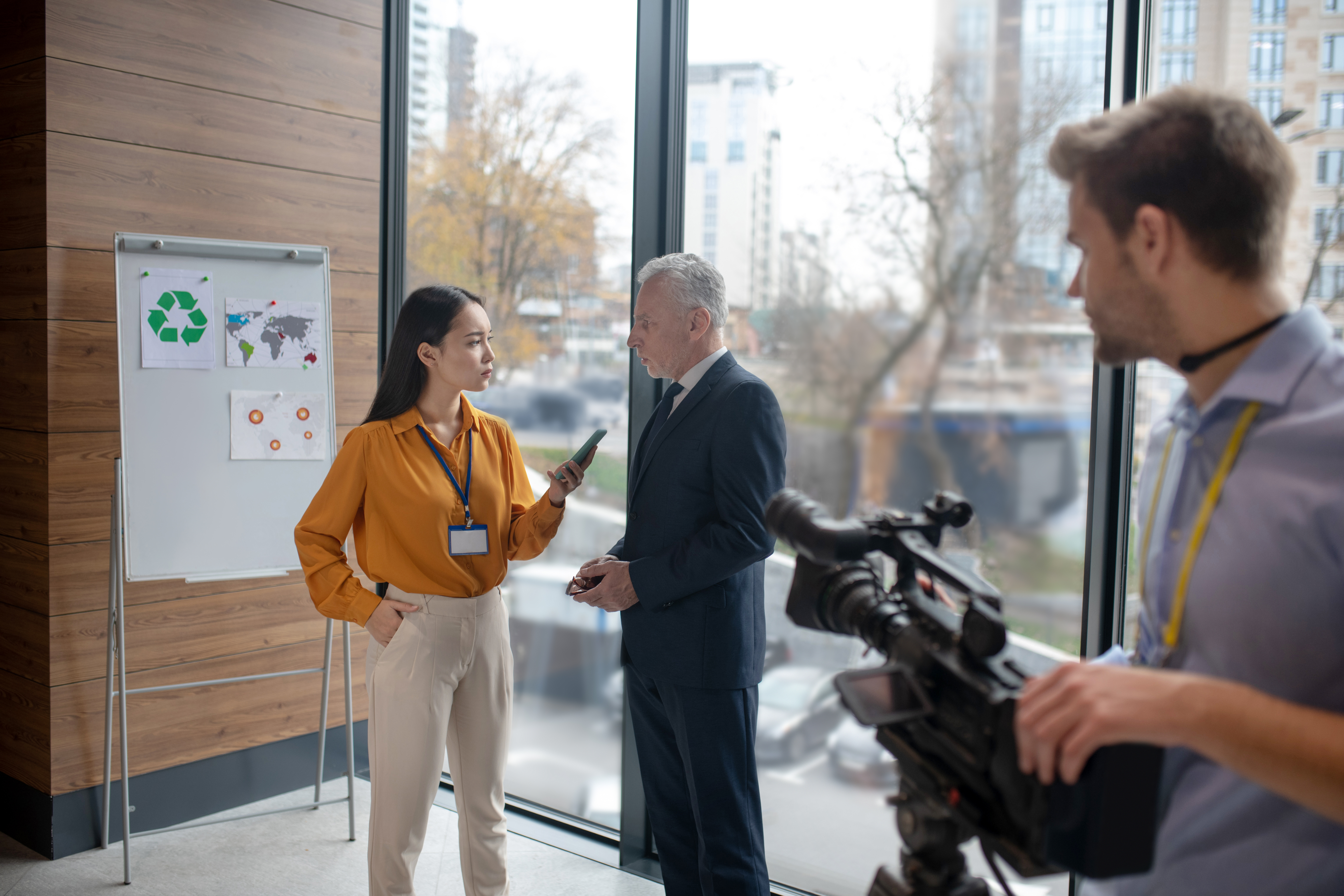 Young asian reporter explaining something to a grey-haired man